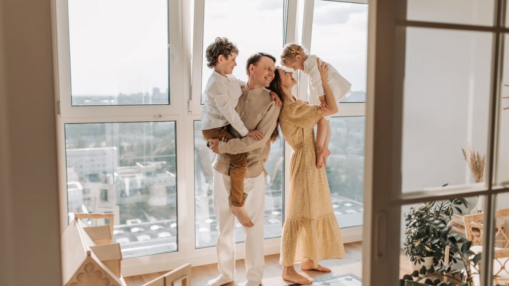 Happy family with children enjoying time together in a sunlit modern apartment.